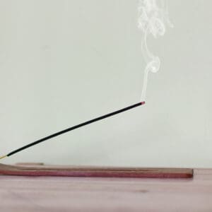 Burning incense stick releasing smoke.