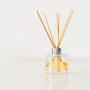 A reed diffuser with yellow liquid on a white surface.