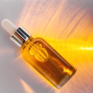 Amber glass dropper bottle with golden liquid and light reflections.